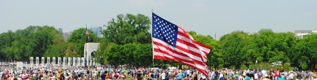 American Flag flying over the National Mall in Washington DC. WWII Monumnet in the background. 4th of July in Washington, DC.